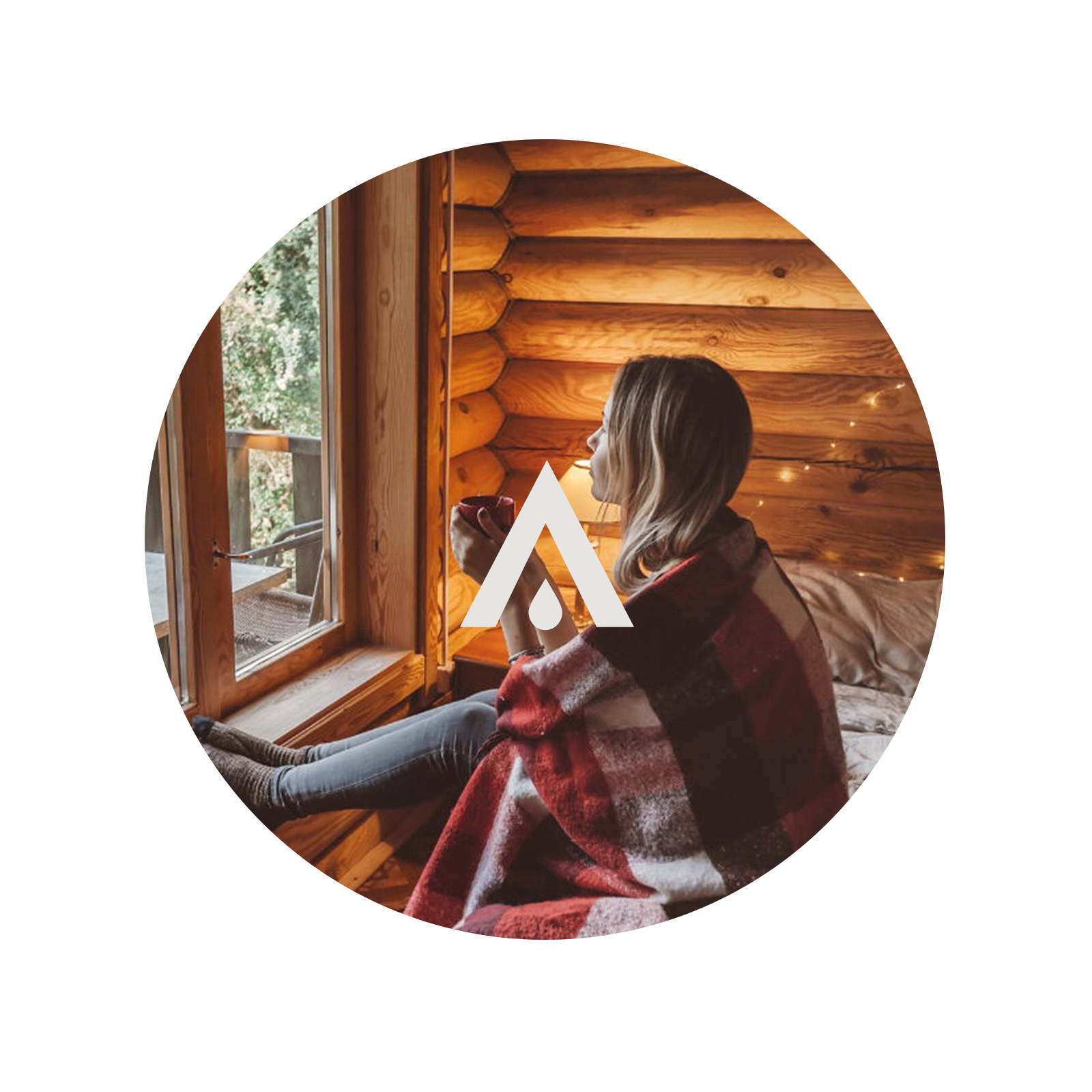 Woman sitting by a window in a cozy cabin, wrapped in a plaid blanket.